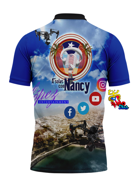 A Solas con Nancy polo shirt featuring a vibrant blue sky with clouds, a central microphone and Puerto Rican flag design, images of two women in red outfits, and "Lopez Entertainment" branding, perfect for fans in 2025, designed by Taino Shirts.