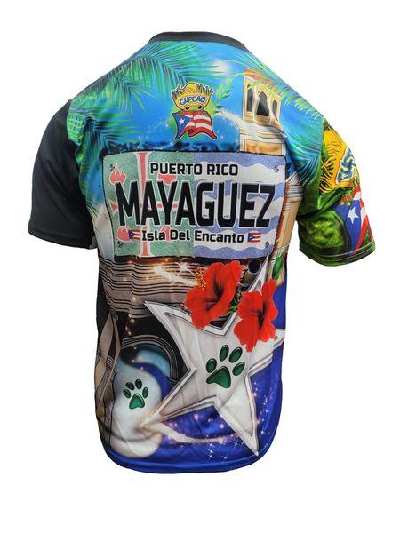 A design of a T-shirt with a front and back view. The front features "La Sultana del Oeste" in bold text, a bulldog, the Puerto Rican flag, and various international flags, with a "Gufeo" cartoon character and flag emblem. The back displays "Mayaguez" on a license plate-style graphic, a red hibiscus flower, a white star with a paw print, and the Puerto Rican flag, with a church and palm trees. The website "www.gufeo.com" is implied in the design context.