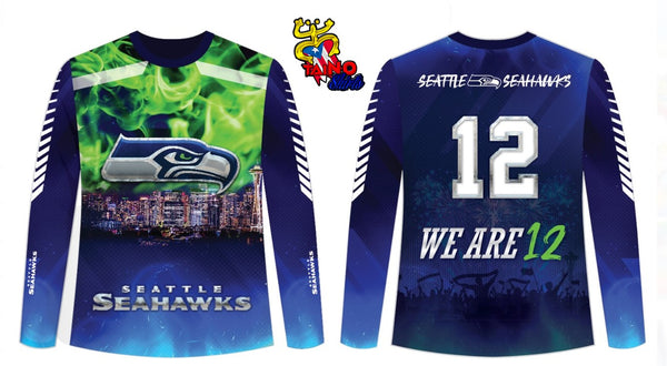 A dynamic t-shirt featuring the Seattle Seahawks design with front and back views. The front showcases the Seahawks logo with a green flame effect, a city skyline, and "SEATTLE SEAHAWKS" text. The back displays the number 12 and "WE ARE 12" with a crowd scene, representing the 12th Man, perfect for NFL and Seahawks fans.