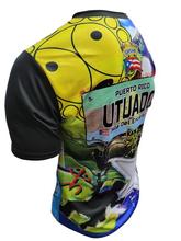 A vibrant t-shirt celebrating Utuado, Puerto Rico as "La Ciudad del Viví" with front and back designs. The front features bold text "La Ciudad del Viví" with a colorful flag collage, a sun emblem, and a blue gradient background with the Puerto Rican flag. The back showcases a rural scene with a horse, a "Utuado Isla del Encanto" sign, and a large star with a Gufeao logo, perfect for expressing Utuado pride and Puerto Rican heritage.